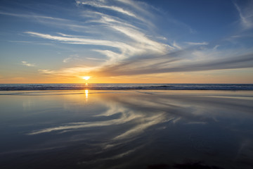 Fototapeta na wymiar Sun setting at beach at low tide in San Diego, California