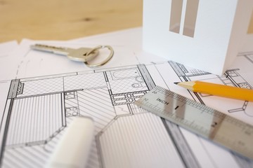House remodel. Drawings of plannings are lain at home on a wooden table with a ruler, a pencil, the house model.