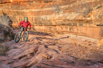 riding fat bike on slickrock at  canyon bottom