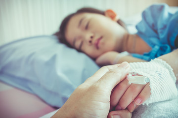 Parent holding child's patient hand for encouragement and empathy.