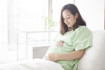 A pregnant woman smiling at a bed in a hospital