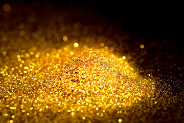 Sprinkle glitter gold dust in the dark textured abstract background elegant for Merry christmas and...