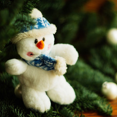 Knitted snowman on a branch of a Christmas tree. knitted Chrismas toys on green fir branches