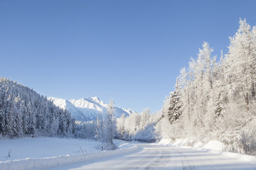 Fototapeta na wymiar Snowy road with mountains