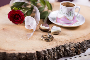Turkish coffee with red rose, heart shaped chocolates and gold rings on wooden  