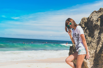 Beautiful young woman in sunglasses posing on the beach of a tropical island of Bali.