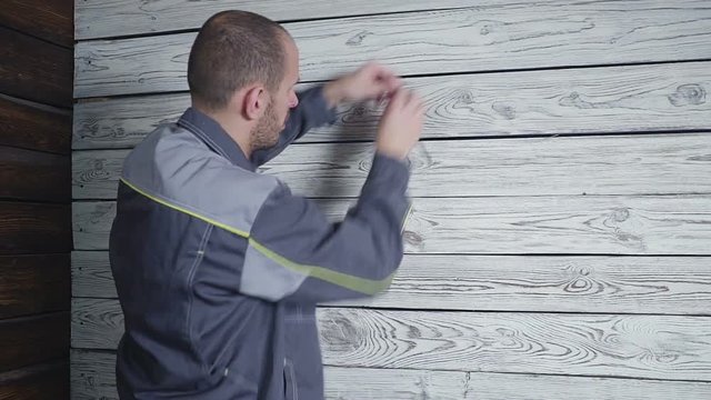 The worker measures a wooden wall with a ruler
