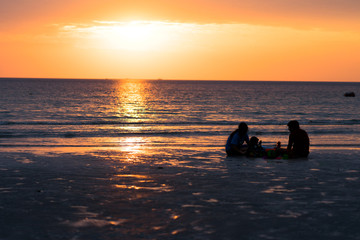 Naklejka na ściany i meble Silhouette happy family enjoying on beach with sunset