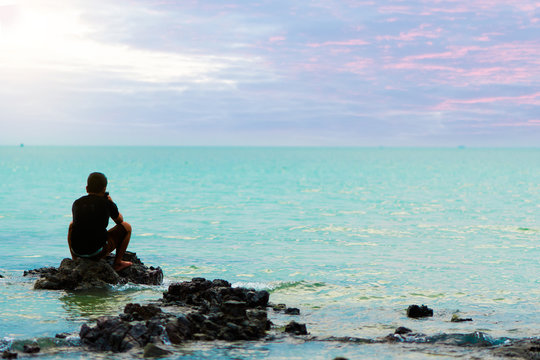 Sad Man sitting on rock in the sea feeling lonely and broken heart