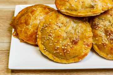 Round mini meat pies on a plate on a table.