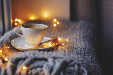 cozy winter or autumn morning at home. Hot coffee with gold metallic spoon, warm blanket, garland...