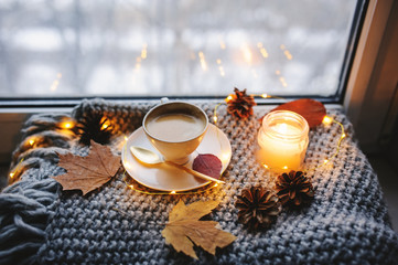 cozy winter or autumn morning at home. Hot coffee with gold metallic spoon, warm blanket, garland...