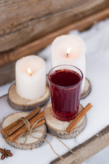 mulled wine on a wooden stand white candles bundle of dry cinnamon sticks on the table with the snow