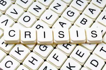 Crisis title text word crossword. Alphabet letter blocks game texture background. White alphabetical letters on black background. White educational toy block with words on board table. Words.