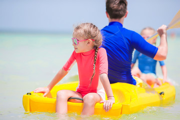 Fototapeta premium Little girls and young dad kayaking during summer vacation