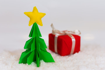 miniature paper pine tree figure with felted star on the top and red gift boxes, selective focus