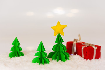miniature paper pine tree figures with felted star on the top and red gift boxes, selective focus