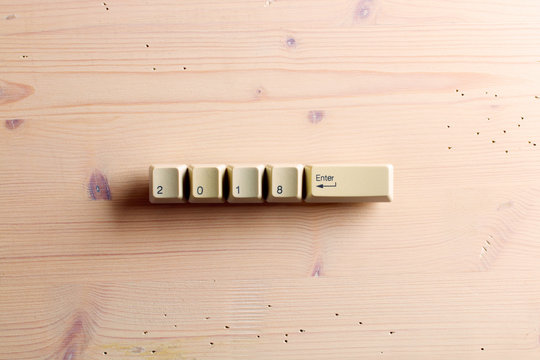 Computer keyboard keys with 2018 enter on a wooden background. New year card.