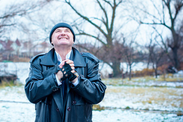 American Mature Happy Man Smiling with good mood at nature outside. Portrait of happy elderly man against winter forest background on a travelling 