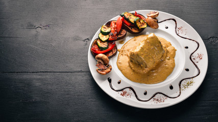 Meat steak with sauce and grilled vegetables. Steak Voronov. On a wooden background. Free space for your text. Top view.