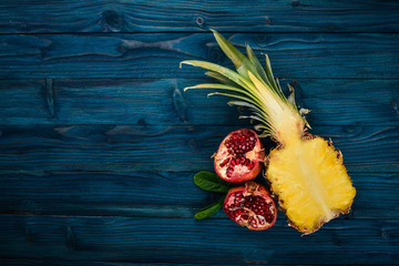 Pineapple and pomegranate. Fresh fruits. On a wooden background. Top view. Free space for text.
