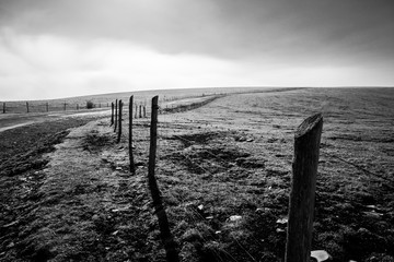 A fence and road on top of a mountain, with low clouds on the horizon