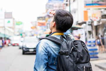 Young independent Asian man tourist backpacker traveling in Khao San road Thailand