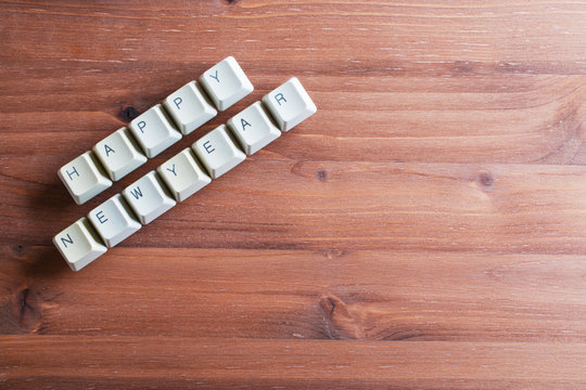 Happy new year card concept on computer keyboard keys on a wooden background