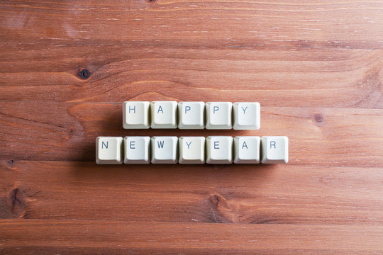 Happy new year card concept on computer keyboard keys on a woode