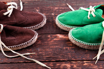 Green and brown suede espadrille shoes on wooden background.