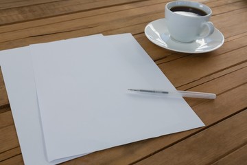 Black coffee and blank paper on wooden plank