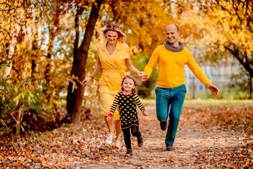 Fototapeta premium The mother ,father and daughter running along park
