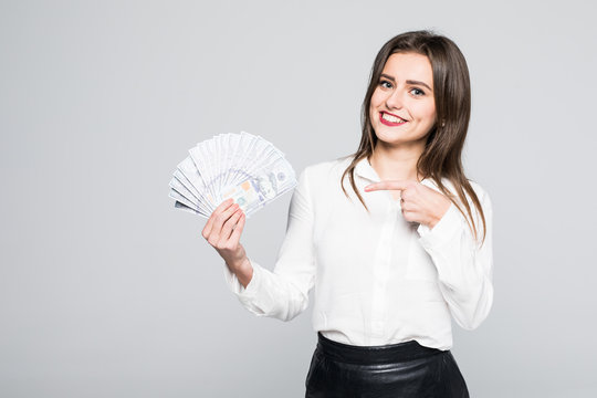 Image of happy young woman standing isolated over white background holding money pointing.