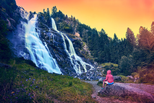 Beautiful woman admiring the Nardis waterfalls in Val di Genova, Adamello-Brenta Natural Park  in the northern Italy