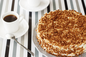 Homemade delicious honey cake with crumb. White tea set on background. Selective focus.