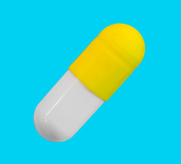 a gelatin capsule with yellow cap isolated on a blue background closeup, top view