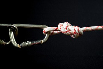 large steel carabiner for mountaineering with a white and red rope on a black background