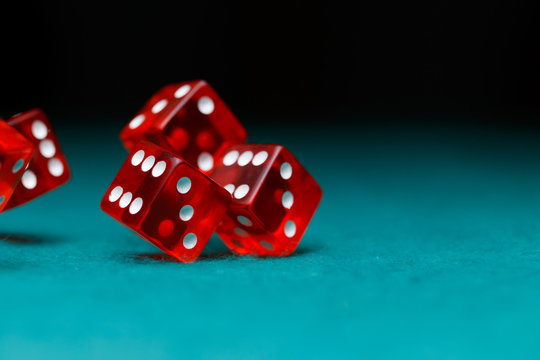 Photo of several red dice falling on green table
