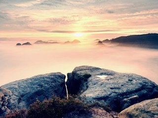 View over sharp sandstone edge into long valley full of first autumnal mist. The misty forest...