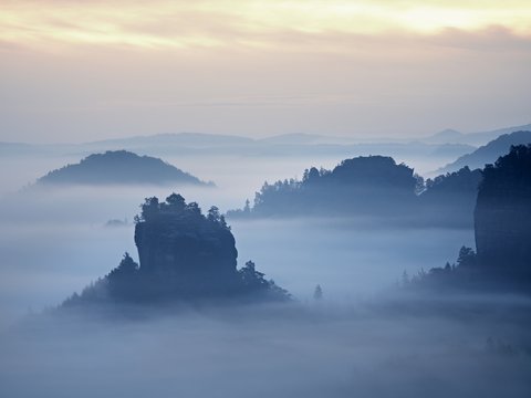 Misty view into beautiful valley of Saxony Switzerland. Sandstone peaks increased from heavy fog.