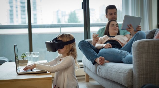 Parents using digital tablet while daughter using virtual