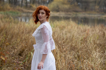 lady with red hair in vintage white dress in forest