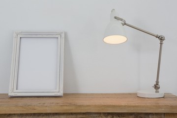 Fototapeta na wymiar Picture frame and illuminated lamp on table