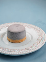 Small round berry cheesecakes on plate and blue background