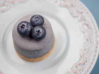 Small round berry cheesecakes on plate and blue background