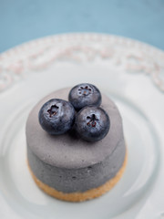 Small round berry cheesecakes on plate and blue background