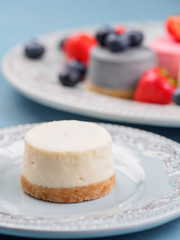 Small round berry cheesecakes on plate and blue background