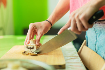 Fototapeta na wymiar Female hands cut into large wooden mushrooms on a cutting board.