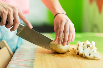 Female hands cut into large wooden mushrooms on a cutting board.