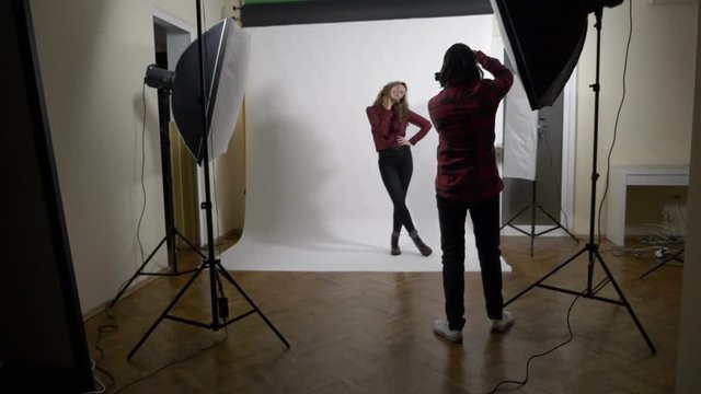Young attractive fashion model at work striking a pose while being photographed from different angles by a passionate photographer in slow motion